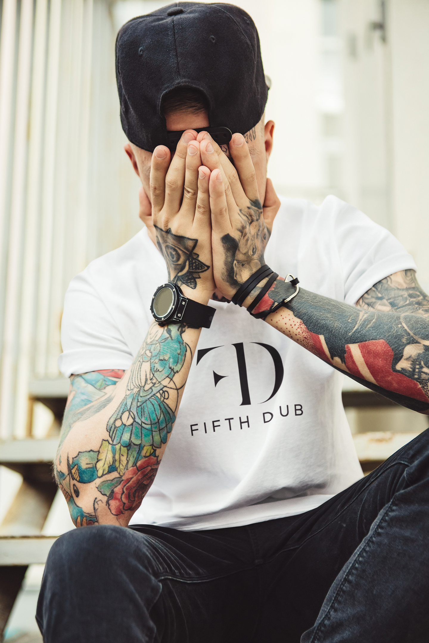 Male model wearing a white Fifth Dub logo t-shirt with Urban Regal streetwear styling, featuring minimal branding and modern fit